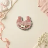Bolacha de especiarias em formato de babador, decorada à mão com glacê real em rosê e branco