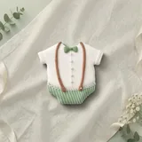 Bolacha de especiarias em formato de macacão, decorada à mão com glacê real em verde slávia e branco, com detalhes delicados e refinados