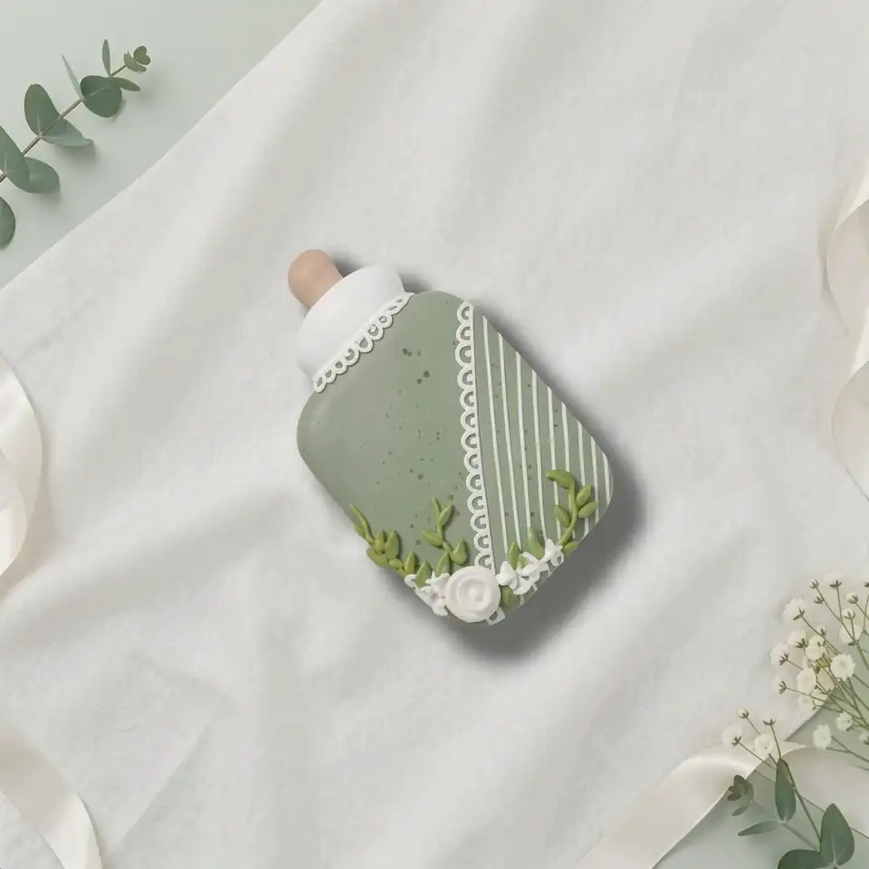 Bolacha de especiarias em formato de mamadeira, decorada à mão com glacê real em verde sálvia e branco, com detalhes delicados e refinados